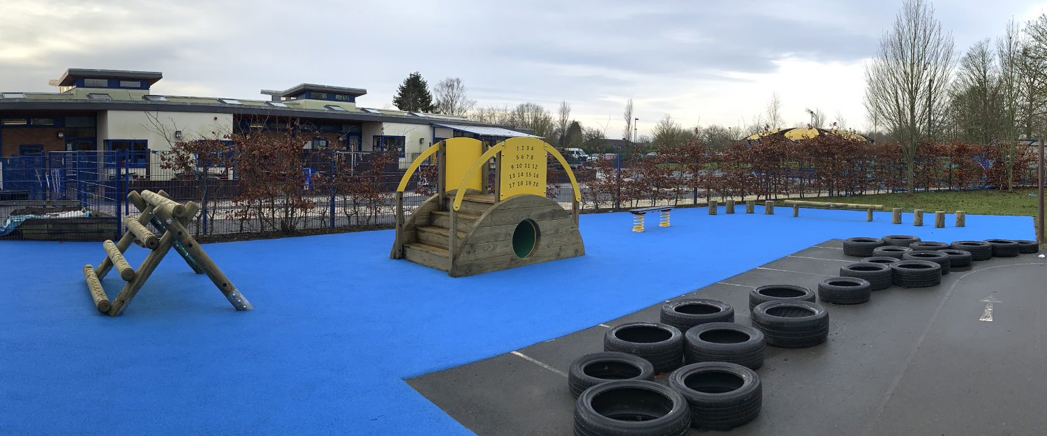 Old Park Nursery Blue Wetpour Safer Surfacing surrounded by tyres with A-frame Mini, Sleeper Tunnel with steps, Spring Wobble Plank, Steeping Logs and Balance Walk