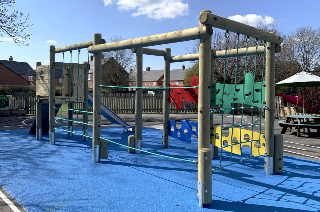timber climbing frame with slide on blue wetpour safer surfacing at Trinity CE Primary School