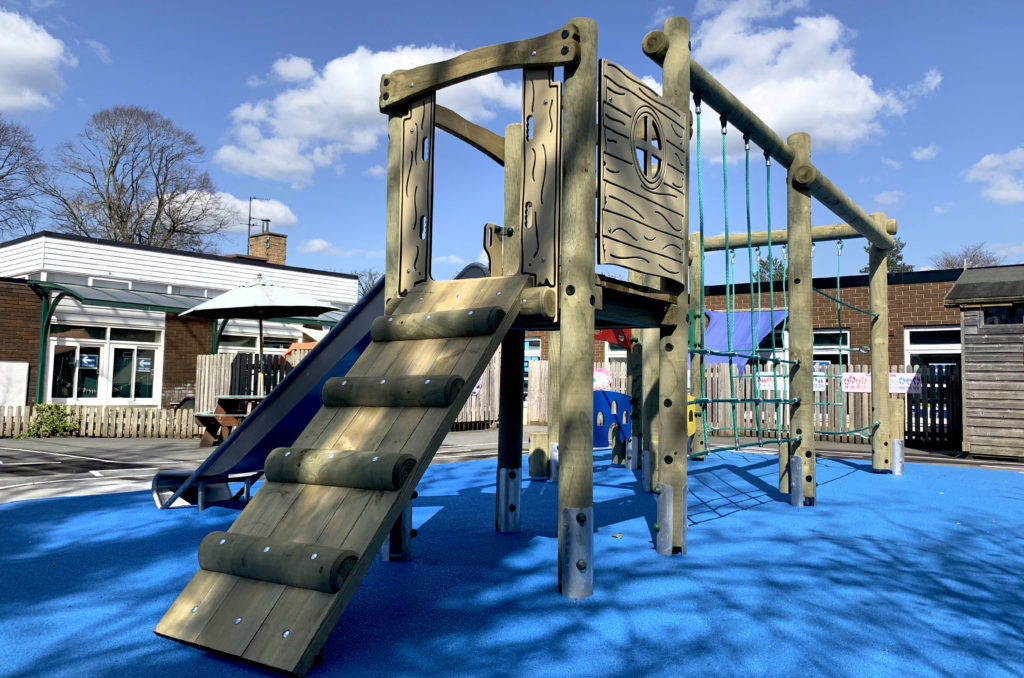 timber climbing frame with slide on blue wetpour safer surfacing at Trinity CE Primary School