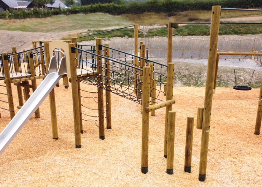 Love2Stay Mid Wales, a timber pole play area with a steel slide to the left side, all on woodchip safer safer surfacing